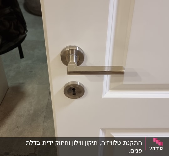 ידית דלת מתכתית על דלת לבנה
